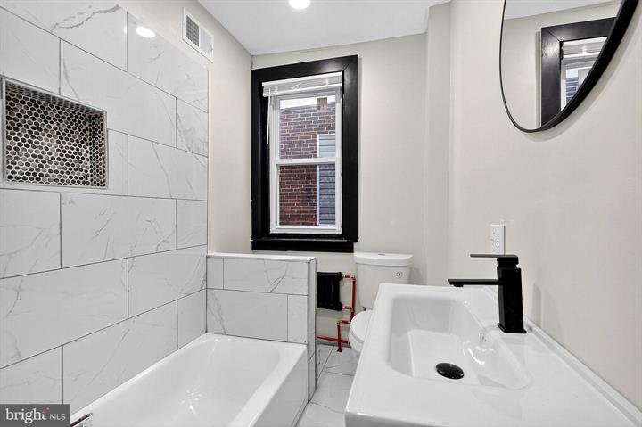 Bathroom with marble-look tile, a tub and a modern sink