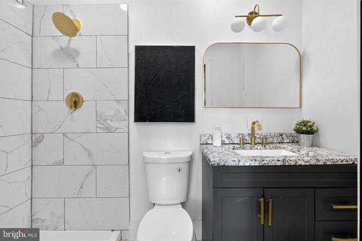 Bathroom with a tiled shower, granite vanity and gold fixtures