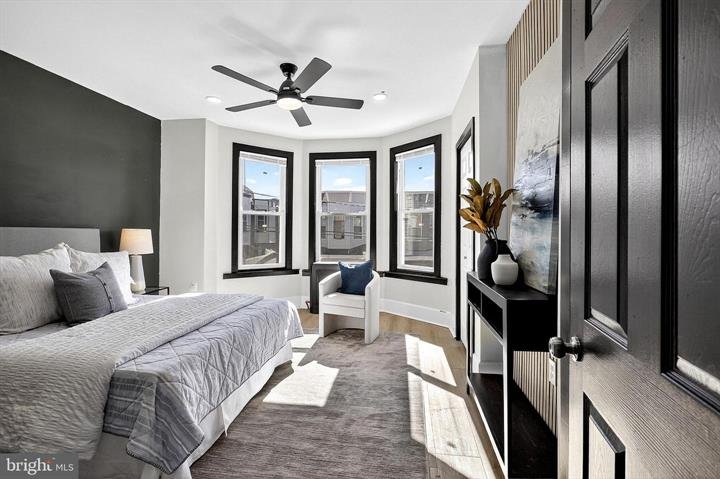 Bedroom with a queen bed, bay windows and a ceiling fan