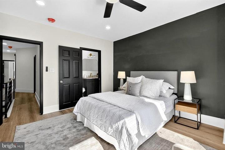 Bedroom with a queen bed, gray bedding and a dark accent wall