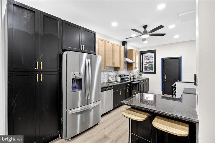 Kitchen with dark cabinets, stainless appliances and a breakfast bar with two stools