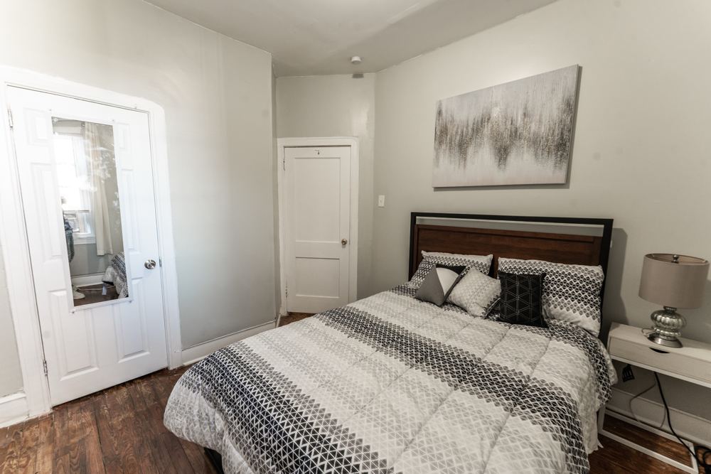 Bedroom with a queen bed, patterned bedding and artwork