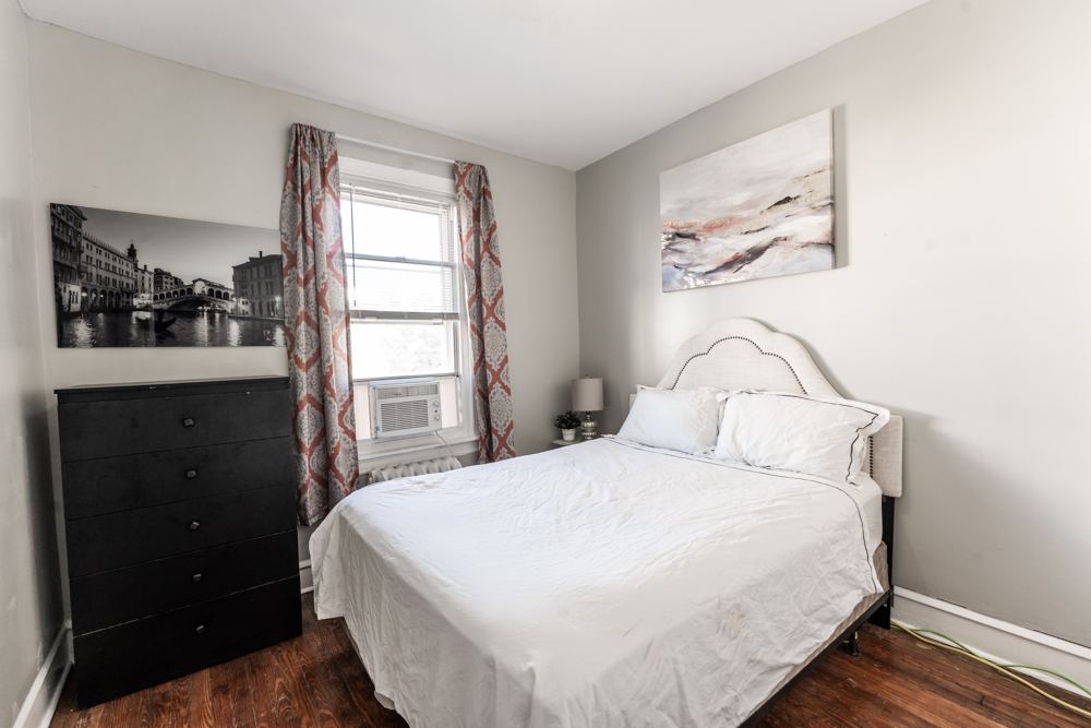 Bedroom with a queen bed, dresser and window air conditioner