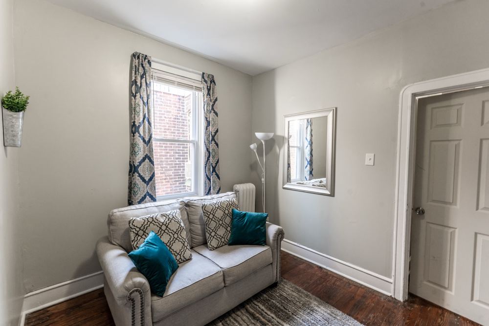 Sitting area with a loveseat, teal pillows and a mirror